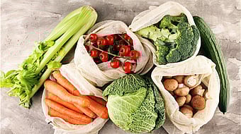 there are different types of vegetables on a grey background. There are tomatoes, cucumber, carrots, cabbage and broccoli.