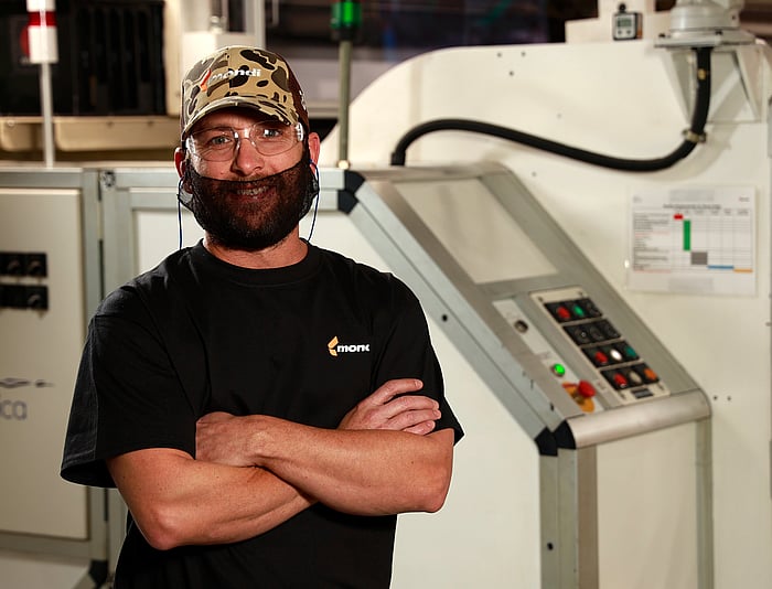 man standing in front of machine smiling in ppe